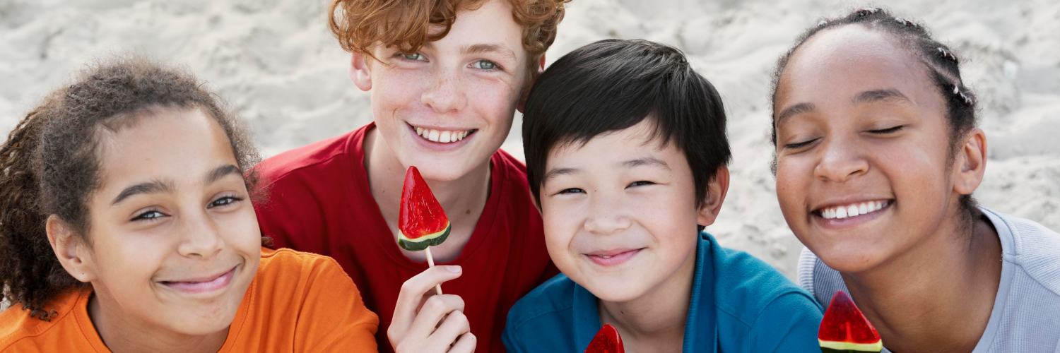 Four smiling children pose for a photo, holding watermelon-shaped lollipops.