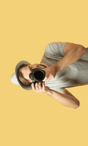 A person wearing a hat holds a camera, taking a photo.