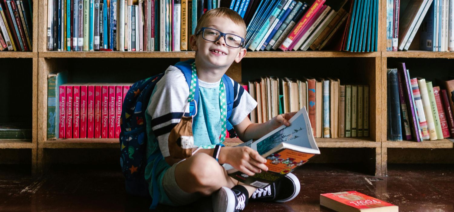 A person sits in a library, surrounded by bookshelves.