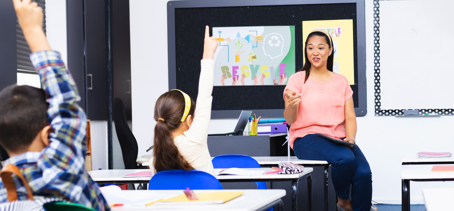 A woman in a pink shirt speaks in a meeting or presentation.