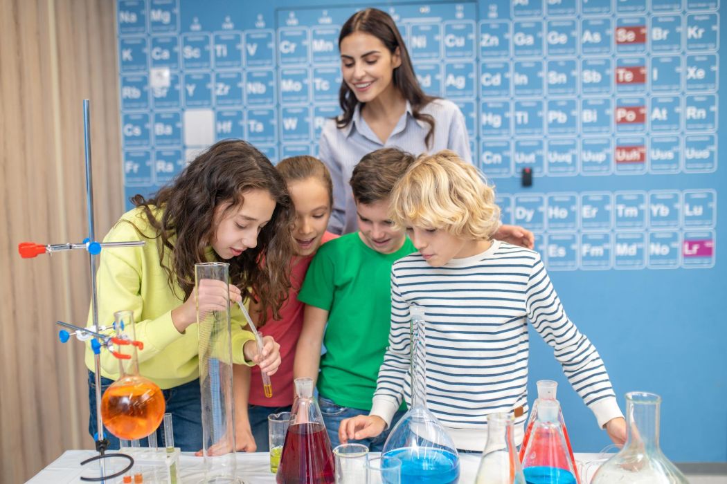 Students and a teacher conduct a science experiment in a lab setting.